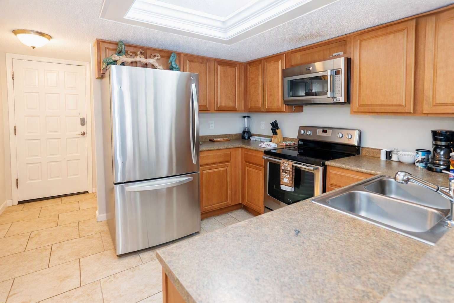 A modern kitchen with stainless steel appliances, wooden cabinets, and a granite countertop.