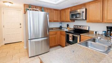 A modern kitchen with stainless steel appliances, wooden cabinets, and a granite countertop.