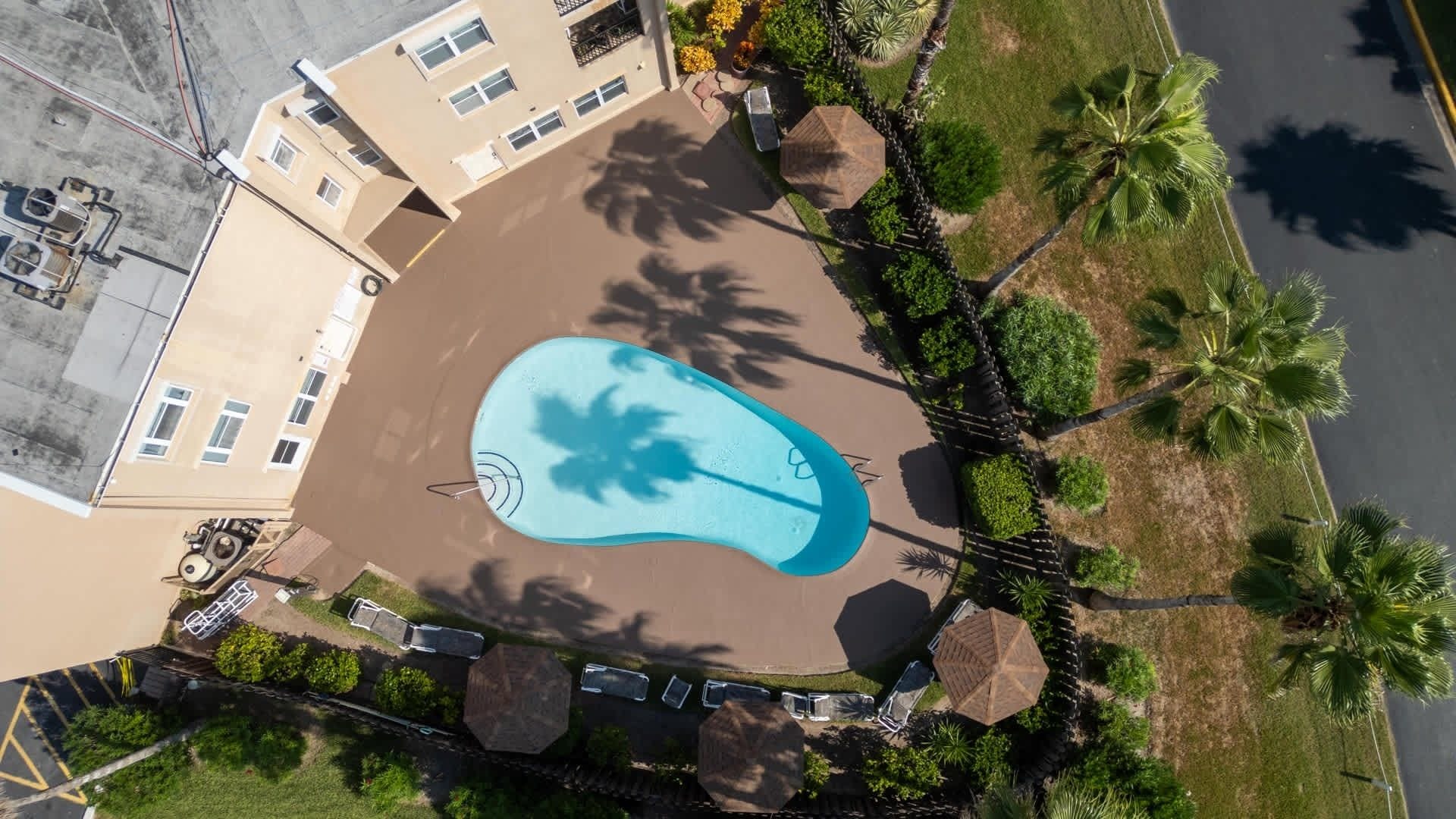 Een vogelperspectief van een resort met een zwembad, omringd door palmbomen en een gebouw met veel ramen.