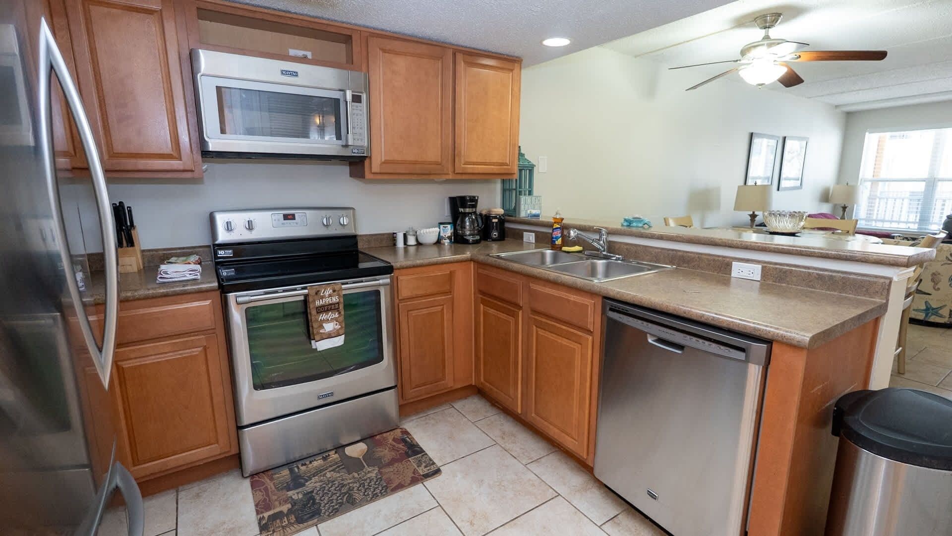 A kitchen with wooden cabinets, stainless steel appliances, a microwave, stove, and a dishwasher.