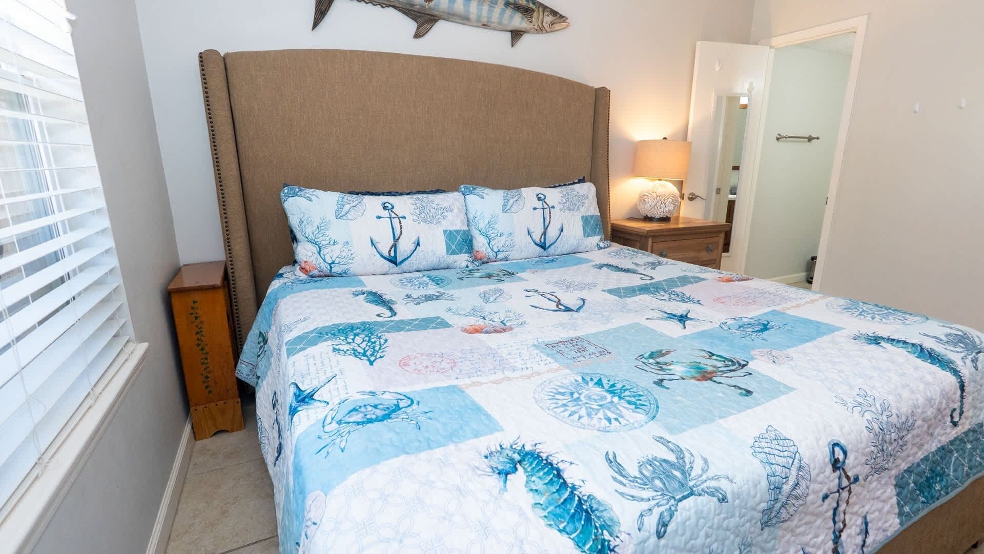 Ein Schlafzimmer mit einem Bett, einem Nachttisch, einer Lampe und einer Fischdekoration an der Wand.