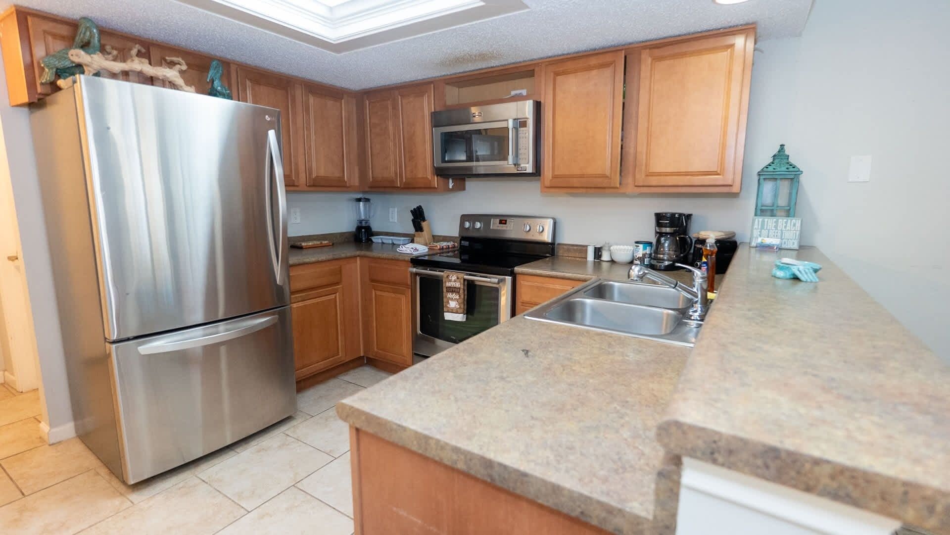 A modern kitchen with stainless steel appliances, wooden cabinets, and a granite countertop.