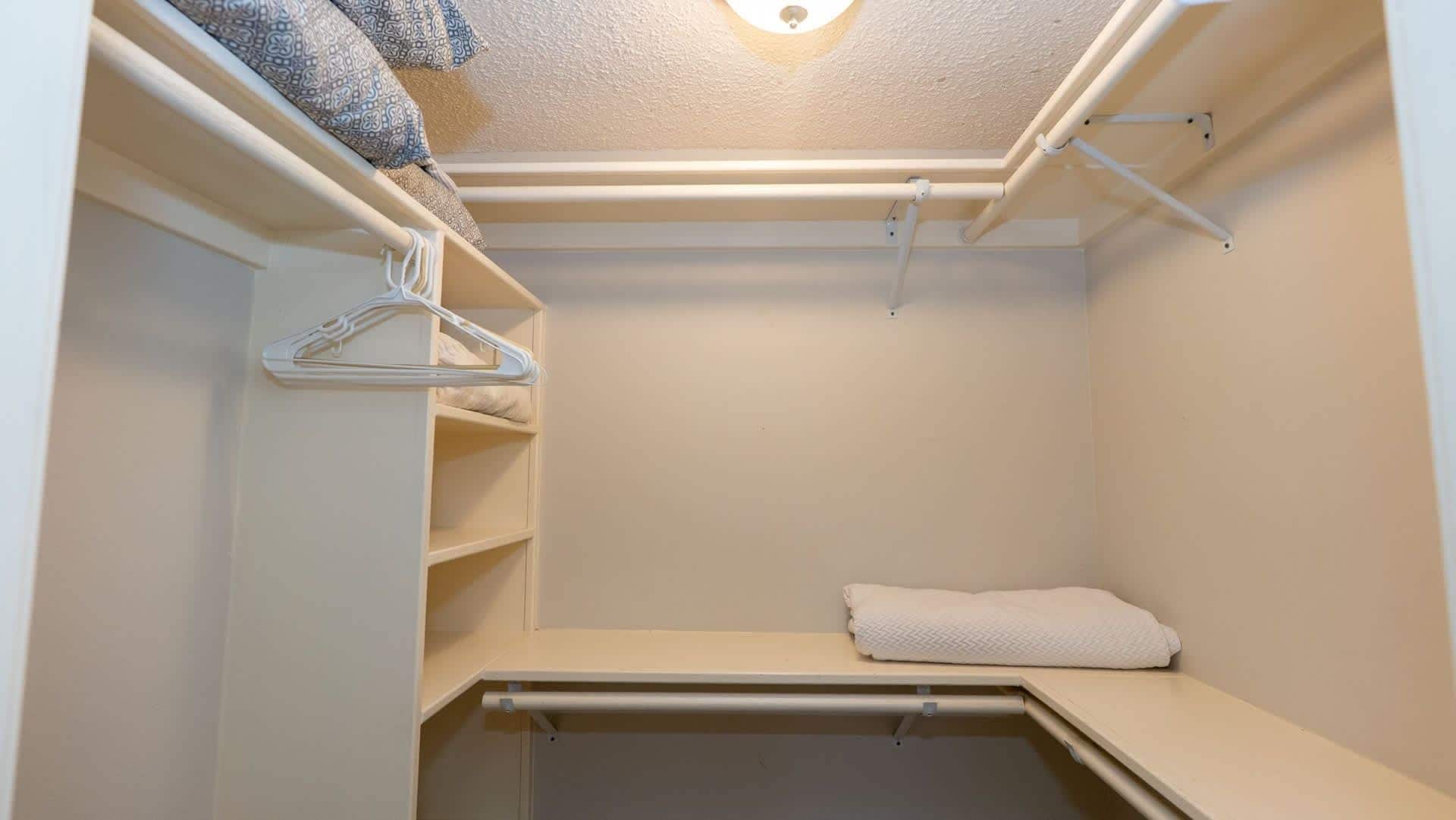 Un vestidor con barra para colgar ropa, estantes y un banco.