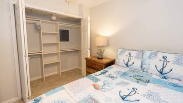 A bedroom with a bed, a nightstand, a lamp, a wardrobe, and a door.