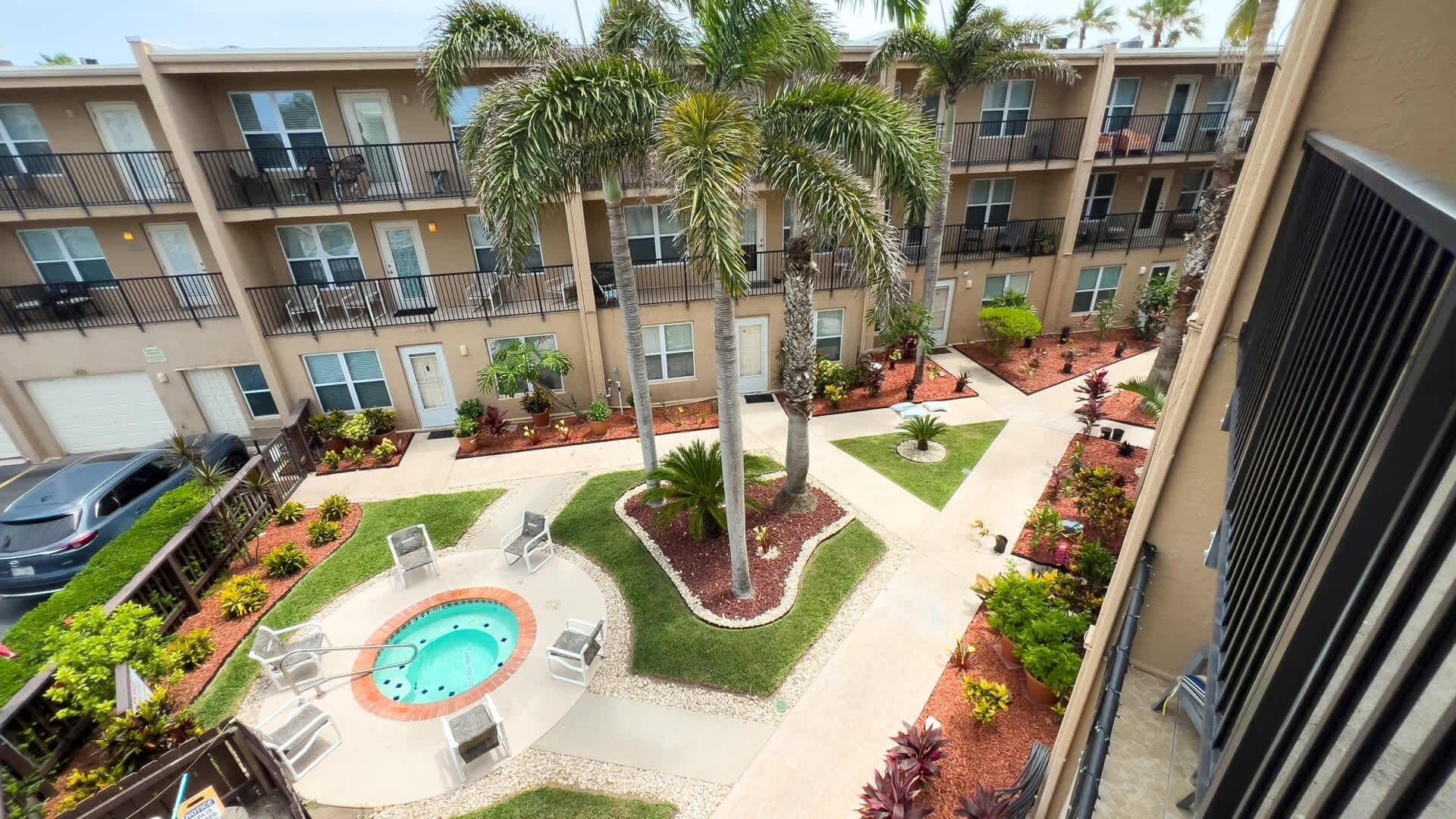 A multi-story residential building with balconies, a swimming pool, and landscaped gardens.
