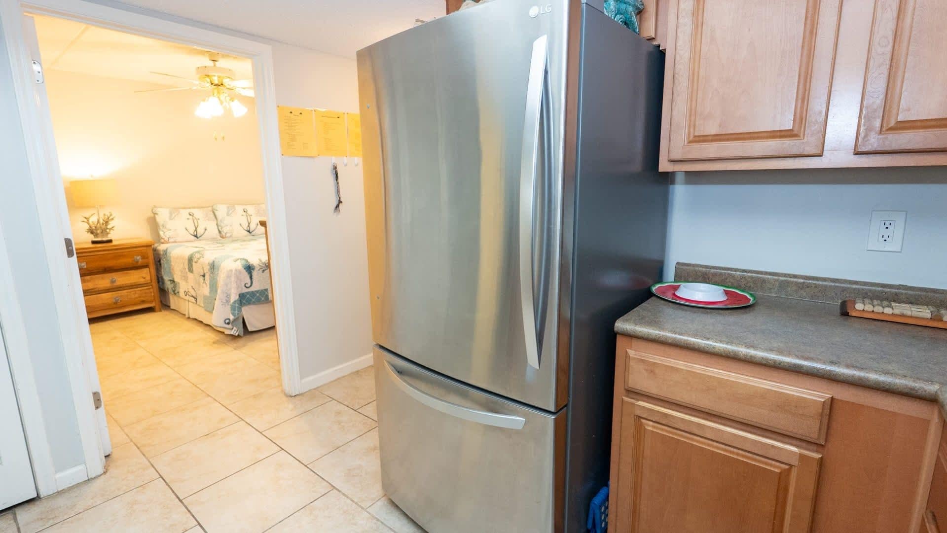 Una cocina con un refrigerador de acero inoxidable, armarios de madera y una encimera con un escurreplatos.