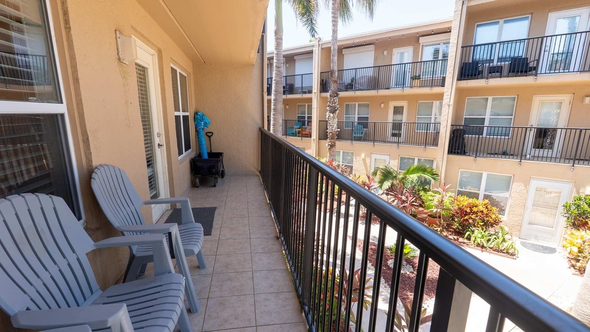 A balcony with chairs, a small table, and a cart.