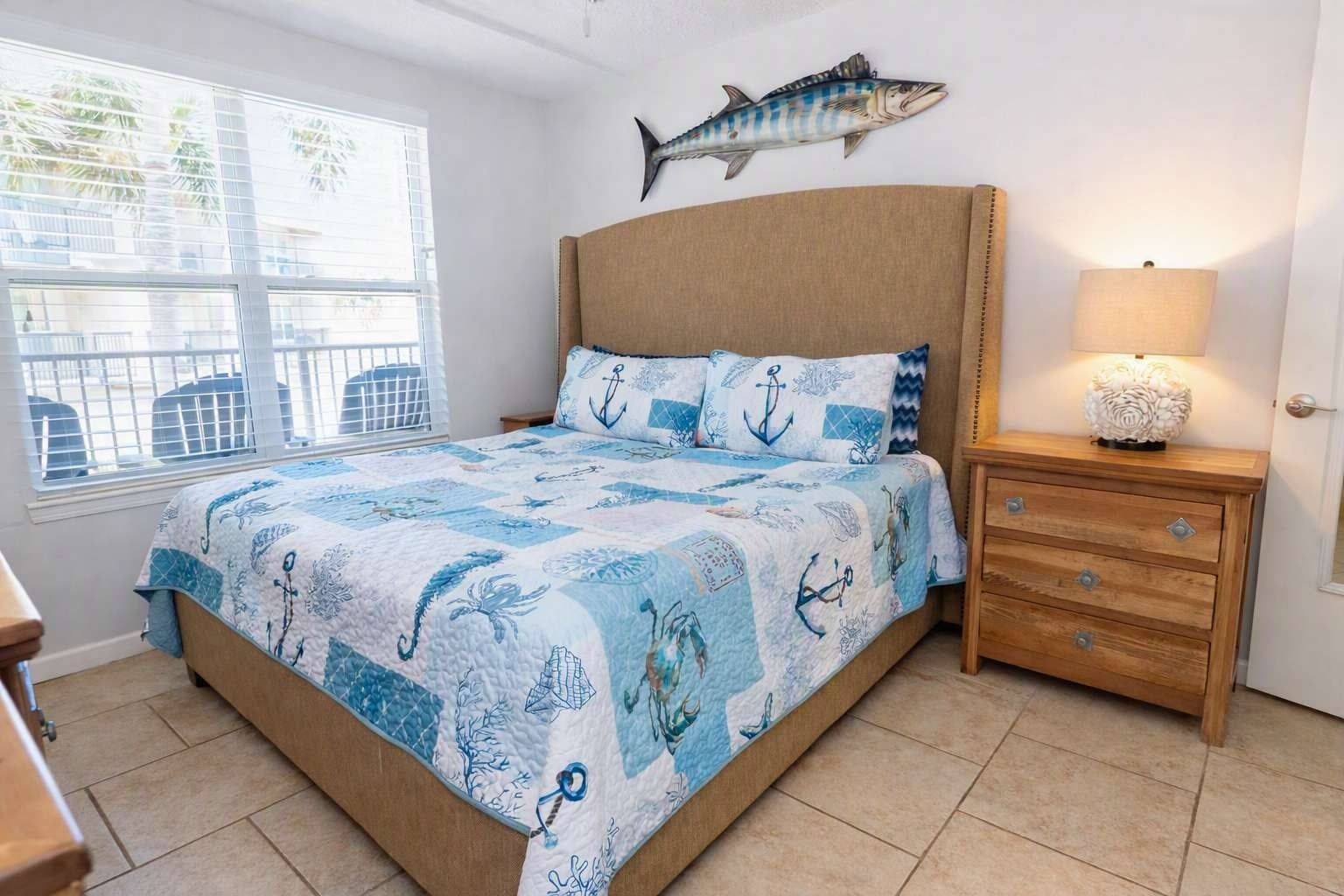 Une chambre à coucher comprenant un lit, une table de chevet, une lampe et un décor mural représentant des poissons.