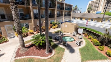 A hotel courtyard with a swimming pool, palm trees, and outdoor seating.