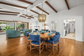 A dining area with a round table, blue chairs, and a hanging light fixture. - Kauai Hoohu Hale 3 Bedroom Home (Koloa)