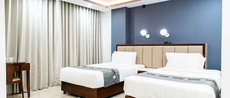 A hotel room with two beds, a desk, and a nightstand.