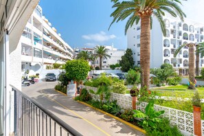 A residential area with white buildings, a street with parked cars, and palm trees. - Carabeo 10 by Casasol (Nerja)