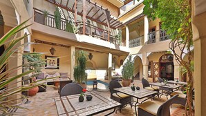 Ein Innenhof mit Außenbestuhlung, einem Pool und mehreren Balkonen.