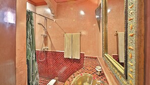 Ein Badezimmer mit roten Fliesen, einer Badewanne, einer Toilette und einer Dusche.