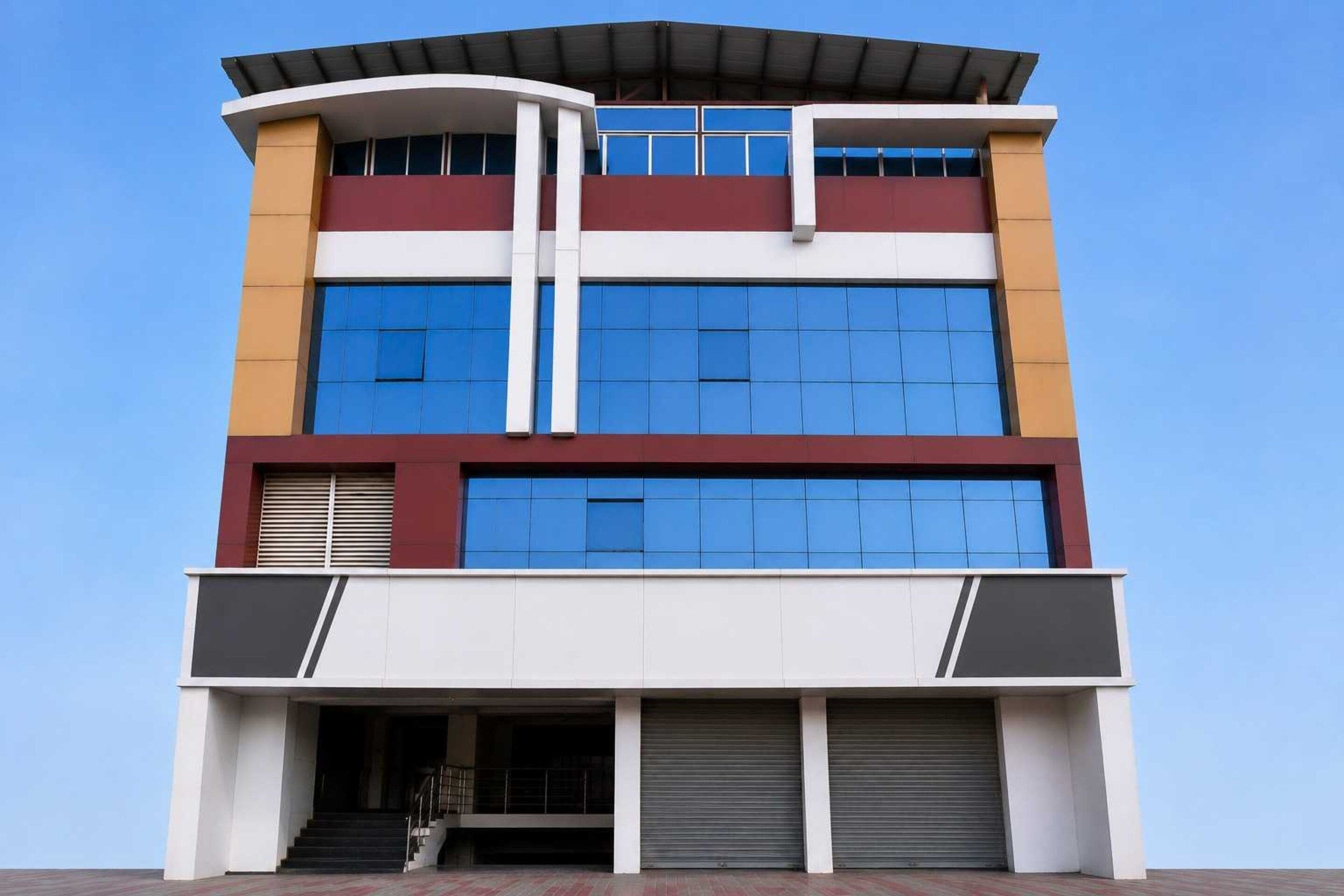 Un edificio de varios pisos con grandes ventanales, techo plano y entrada cubierta.