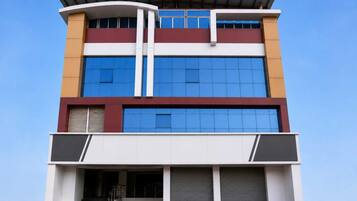 Un edificio de varios pisos con grandes ventanales, techo plano y entrada cubierta.