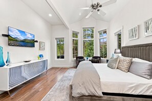 Ein Schlafzimmer mit Bett, Schreibtisch, Fernseher und Deckenventilator.