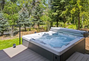 Ein Whirlpool auf einer Holzterrasse, umgeben von Bäumen.