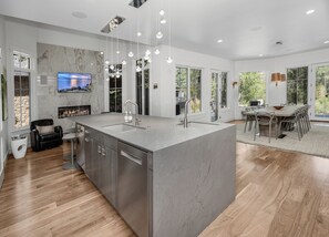 A modern kitchen with a large island, built-in appliances, and a dining area with a view. - Exceptional Arrowhead Riverfront Retreat | Hot Tub & 2-Car Garage (Edwards)