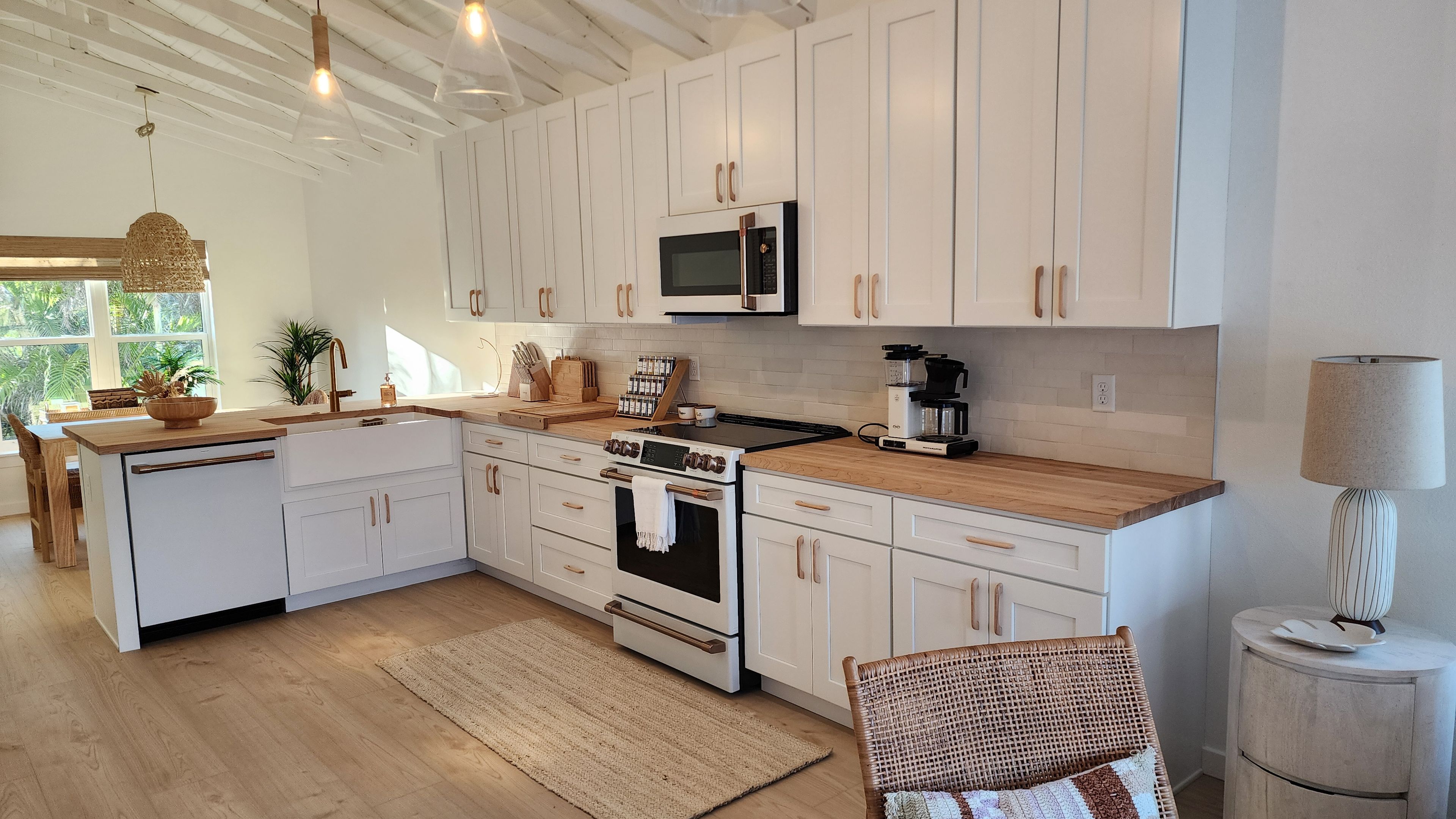 A modern kitchen with white cabinetry, a built-in oven, a microwave, and a coffee maker.