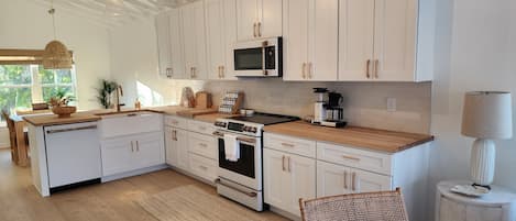A modern kitchen with white cabinetry, a built-in oven, a microwave, and a coffee maker.