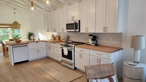 A modern kitchen with white cabinetry, a built-in oven, a microwave, and a coffee maker. - 2-Bedroom Nature Lovers Escape (Sanibel)
