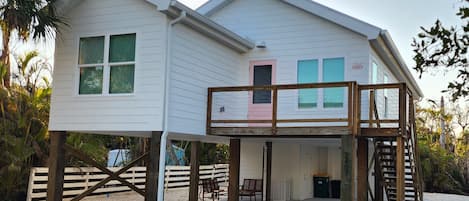A two-story house with a wooden deck and a staircase leading to the upper level.