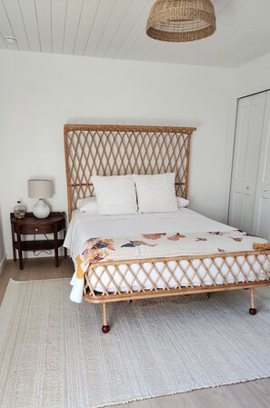 A bed with a woven headboard, a bedside table with a lamp, and a floral-patterned bedspread. - 2-Bedroom Nature Lovers Escape (Sanibel)