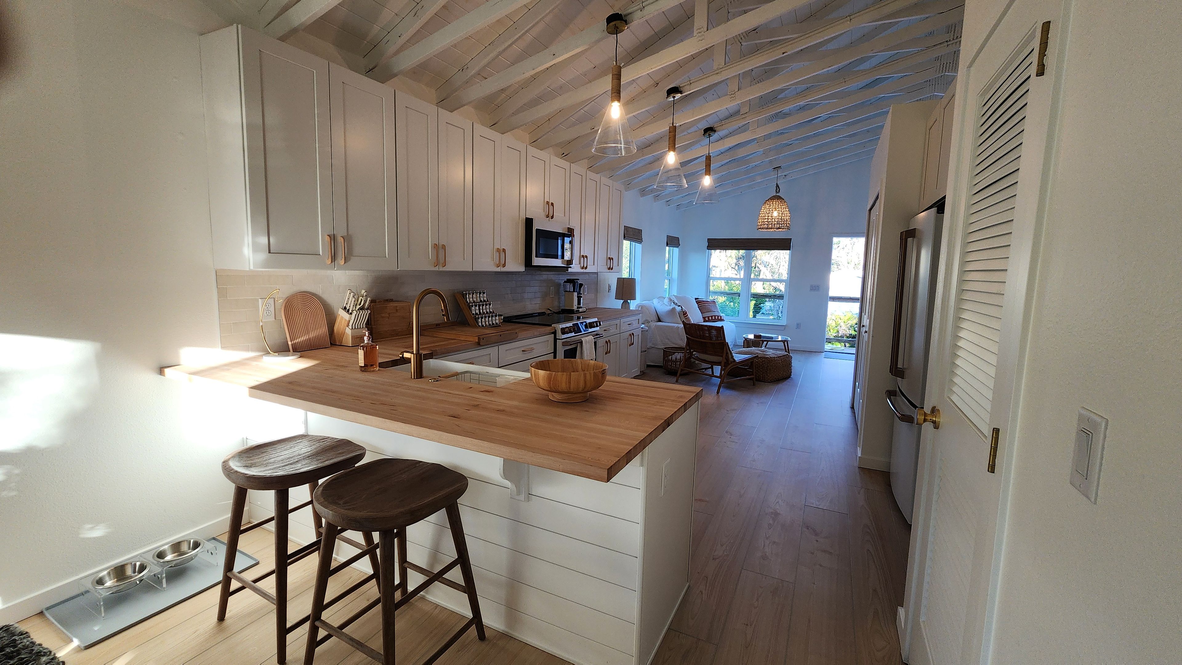 A modern kitchen with white cabinets, a wooden island, and pendant lighting.