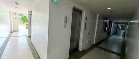 Ein Hotelgang mit einem Fluchtwegschild, einem Telefon und einer Tür.