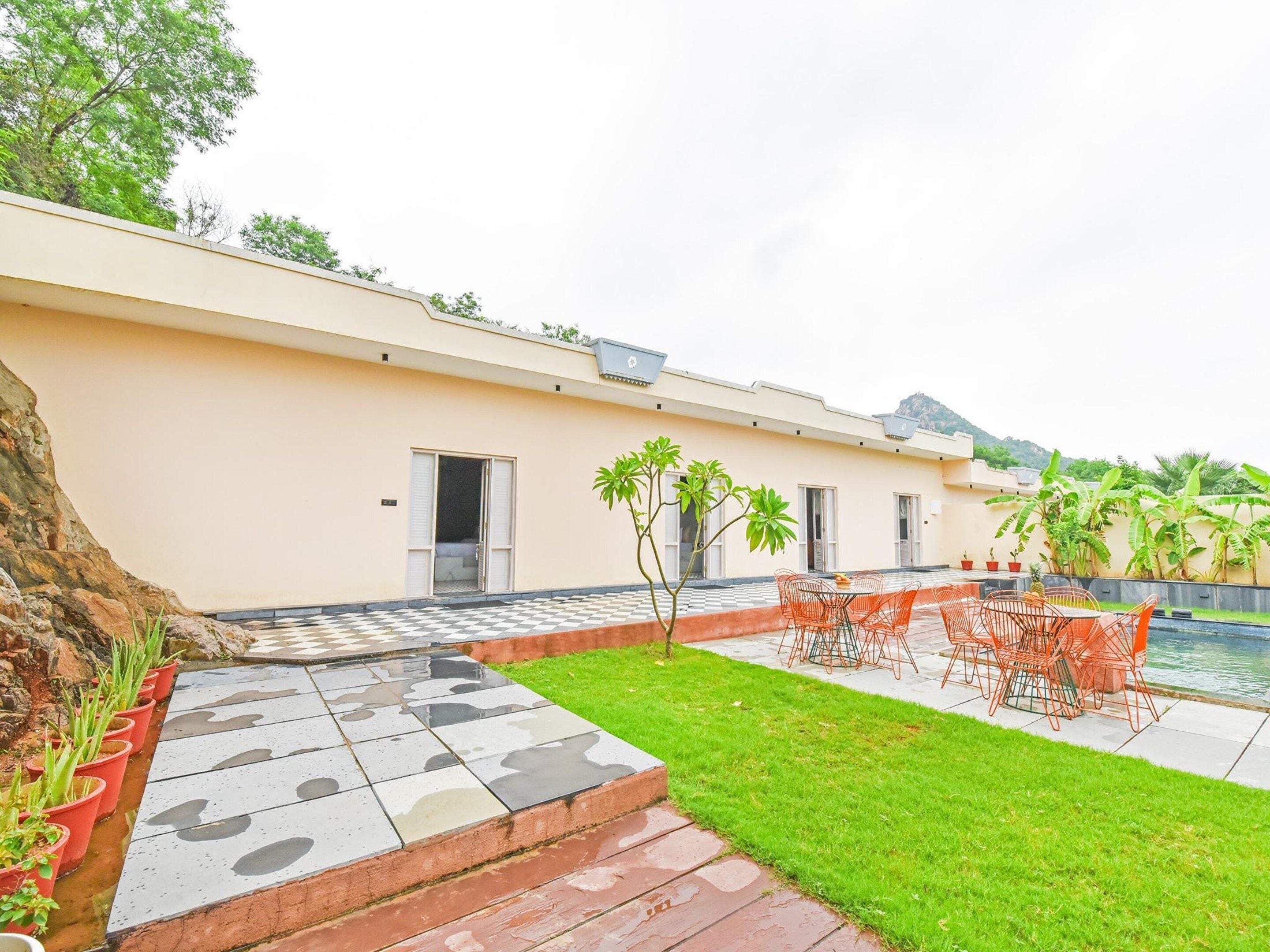 A residential property with a swimming pool, outdoor seating, and a well-maintained lawn.