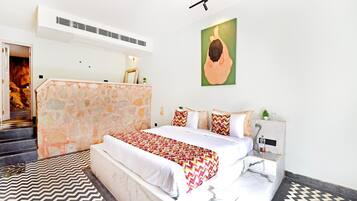A hotel room with a bed, a stone accent wall, a painting, and a patterned rug.