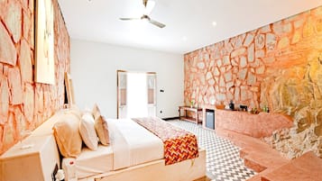 A bedroom with a bed, a desk, and a stone wall.