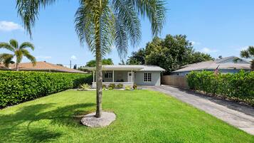 A residential property with a well-maintained lawn, a single-story house, and a surrounding fence.