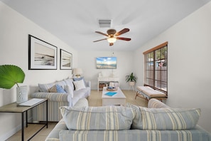 Sala de estar com sofá, mesa de centro e ventilador de teto.
