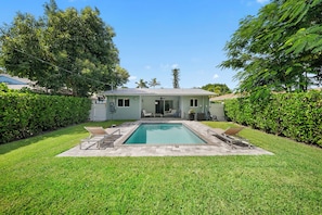 A residential property with a swimming pool, a covered patio, and a lawn. - 2BR Queen Suites • Heated Pool & BBQ • Minutes to the Beach (Naples)