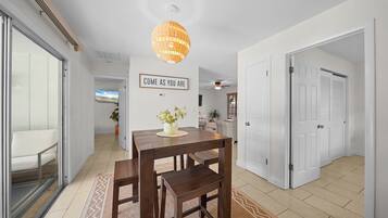 A modern interior with a dining area featuring a wooden table and chairs, a hanging light fixture, and a motivational wall sign.