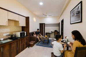 A compact living space with a kitchenette, a dining area, and a seating area. - AVM COMFORT INN (Bengaluru)