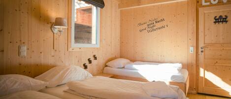 Una habitación tipo cabaña de madera con dos camas, una ventana y una pared con un letrero.