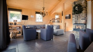 A cozy cabin interior with a stone fireplace, a sofa set, and a television mounted on the wall. - Cabin in Turrach With Sauna and Balcony (Stadl-Predlitz)