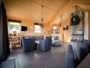 A cozy cabin interior with a stone fireplace, a sofa set, and a television mounted on the wall. - Cabin in Turrach With Sauna and Balcony (Stadl-Predlitz)