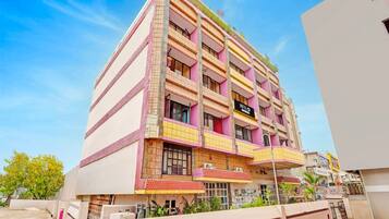 Un hotel de varios pisos con balcones, una señal que indica que es un hotel y un cielo despejado.