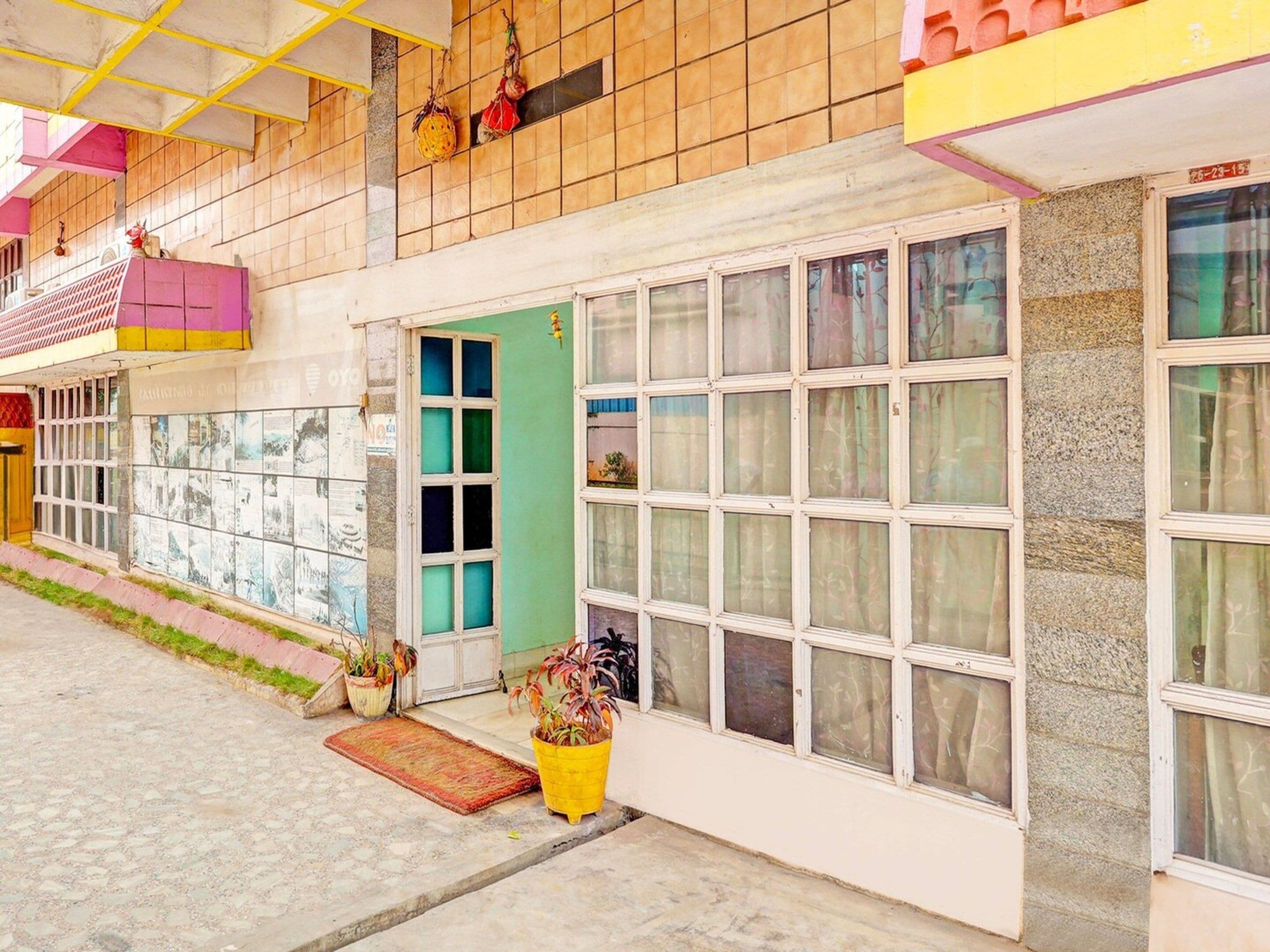 A building with a green door, multiple windows, and a tiled facade.