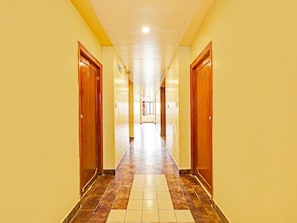 A long, narrow hotel corridor with wooden doors on both sides and a tiled floor. - Premium Hotel sbt (Visakhapatnam)