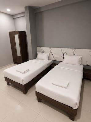 A hotel room with two single beds, a wardrobe, and a marble headboard. - Hotel Shivaaye Inn (Lalpur)