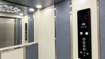 An elevator interior with a digital display, control buttons, and a metallic elevator door.