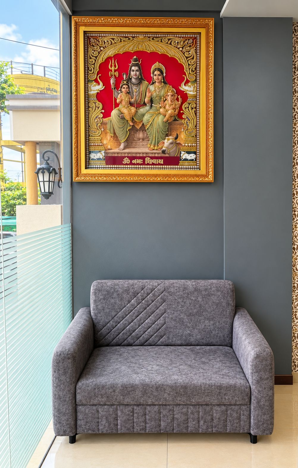 A grey sofa in a room with a framed religious painting on the wall.