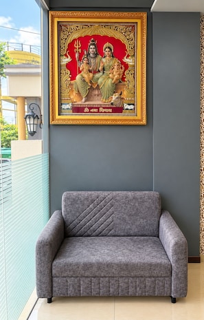 A grey sofa in a room with a framed religious painting on the wall.