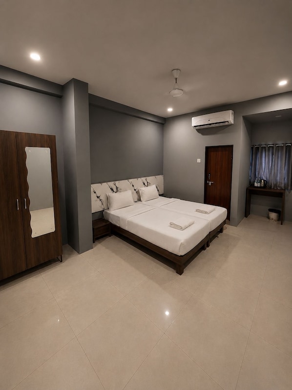 A modern bedroom with a large bed, a wardrobe, an air conditioning unit, and a bathroom with a shower curtain.
