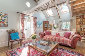 A cozy living room with a glass coffee table, a red sofa, a patterned rug, and a wooden bookshelf. - Traditional Barn Conversion With Lots of Character Features | Stabal-Derwin (Garndolbenmaen)